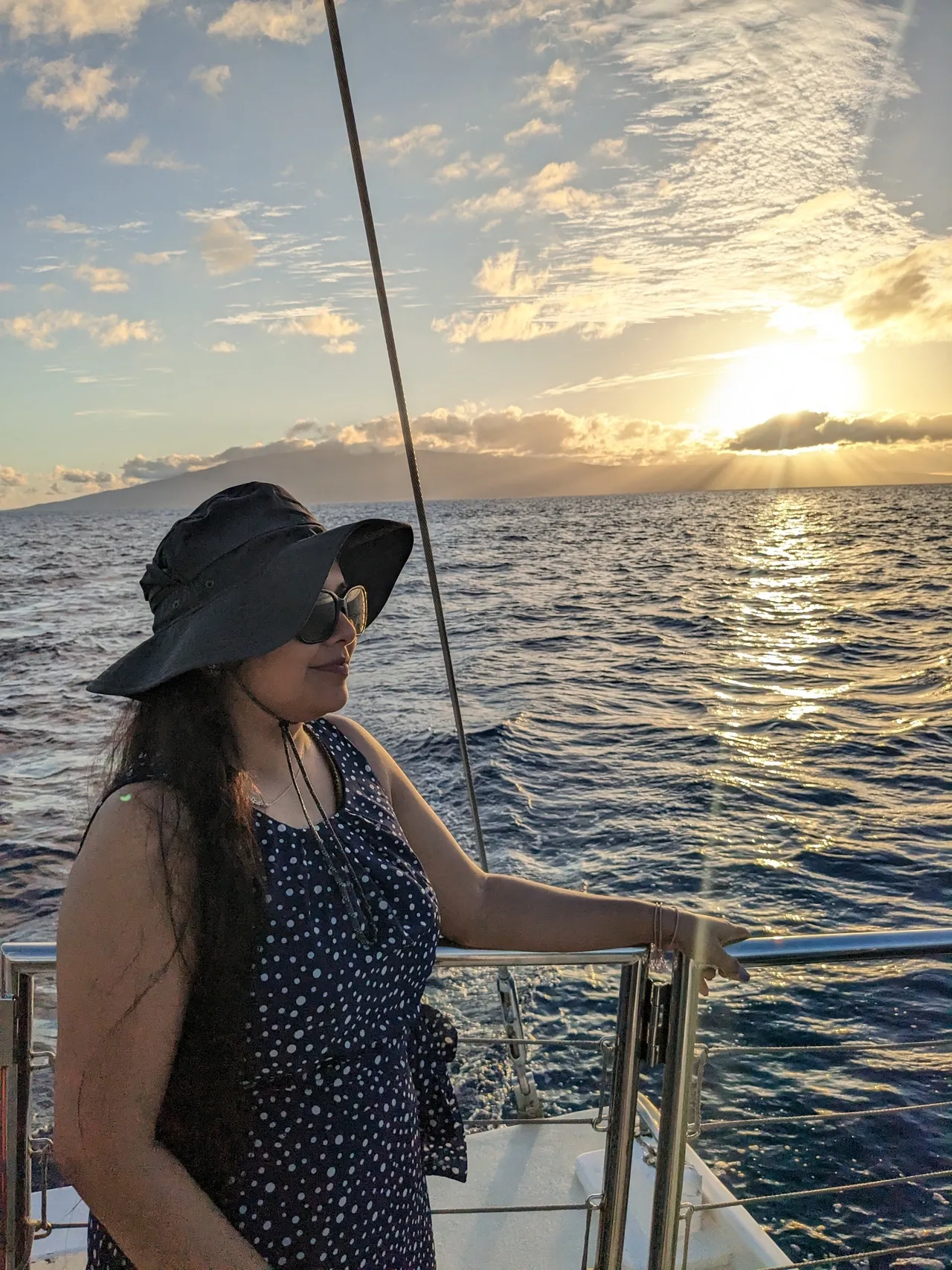 A woman in a hat and sunglasses on a boat.