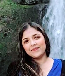 A woman standing in front of a waterfall.