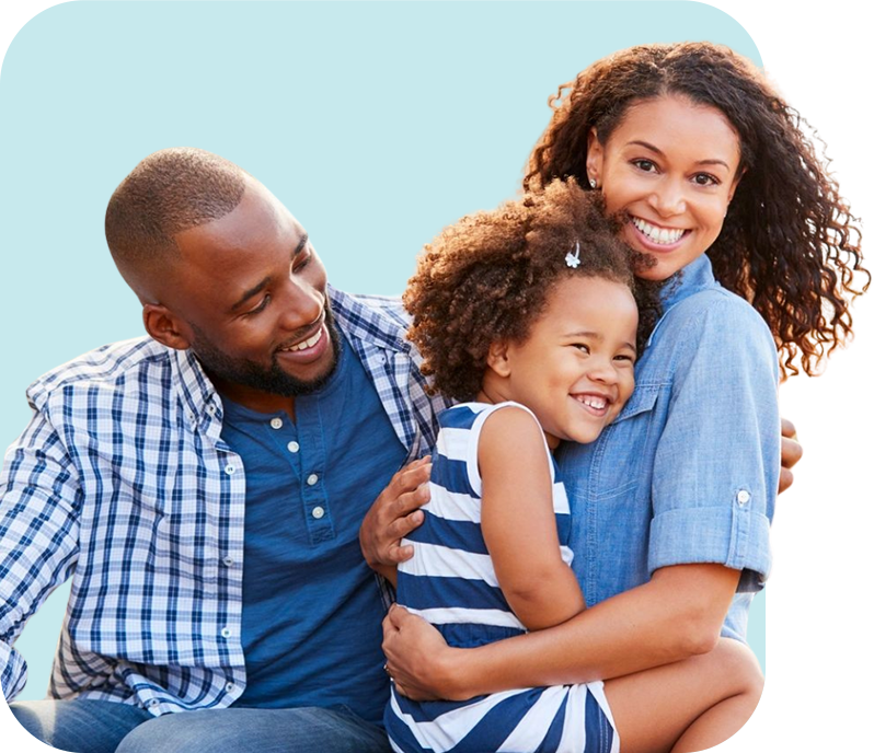 A man and woman hug a young girl while they smile.