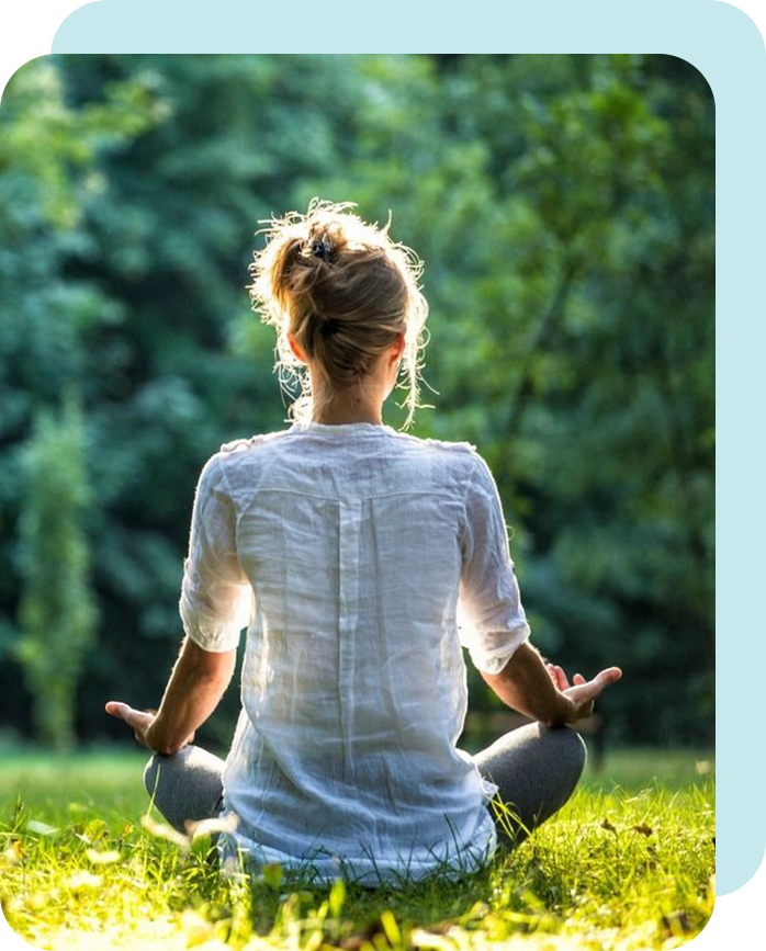 A woman sitting in the grass with her hands up.