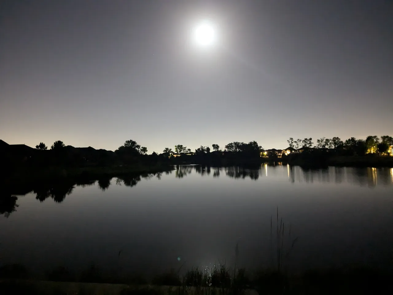 A full moon over the water at night.