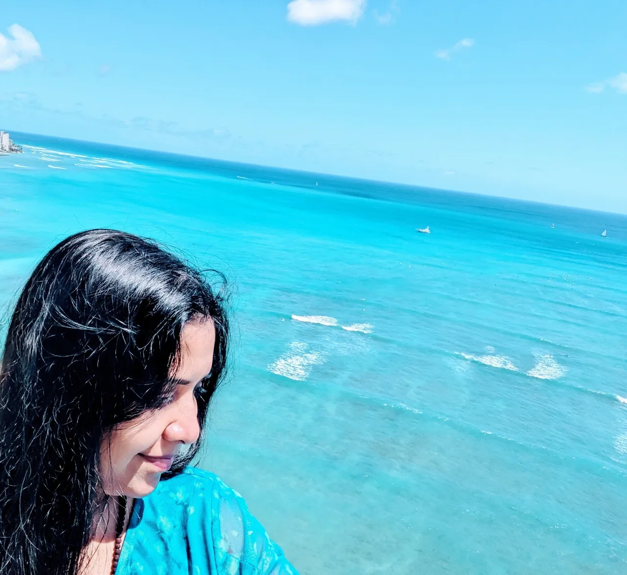 A woman standing on the beach looking at the ocean.