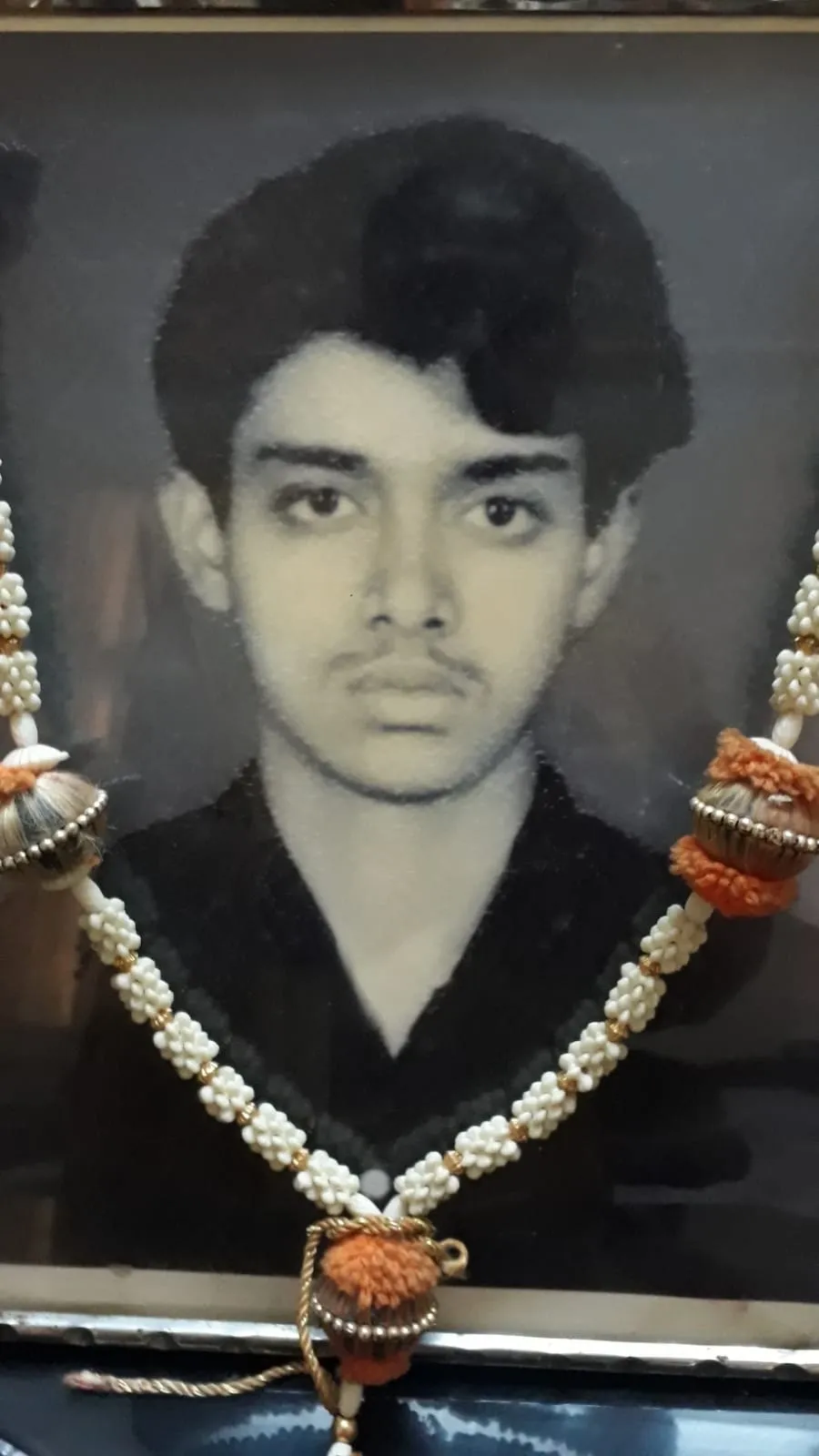 A man wearing a necklace of pearls and orange beads.