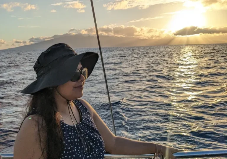 A woman in a hat and sunglasses on a boat.