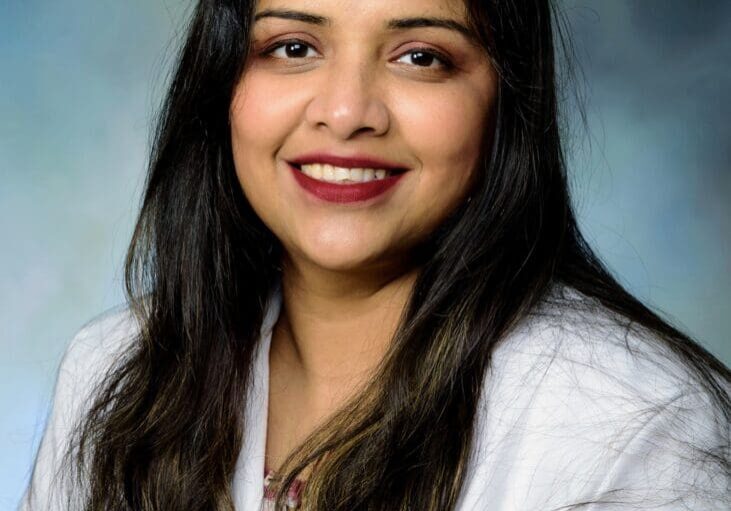 A woman in white lab coat smiling for the camera.