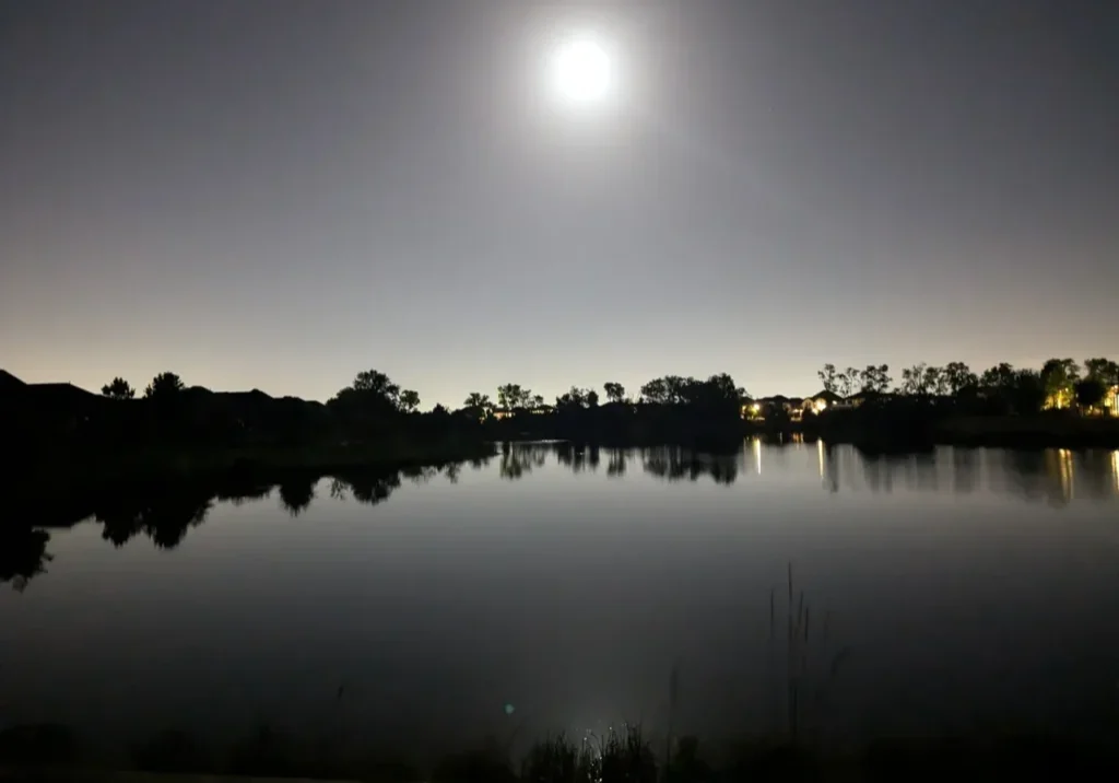 A full moon over the water at night.