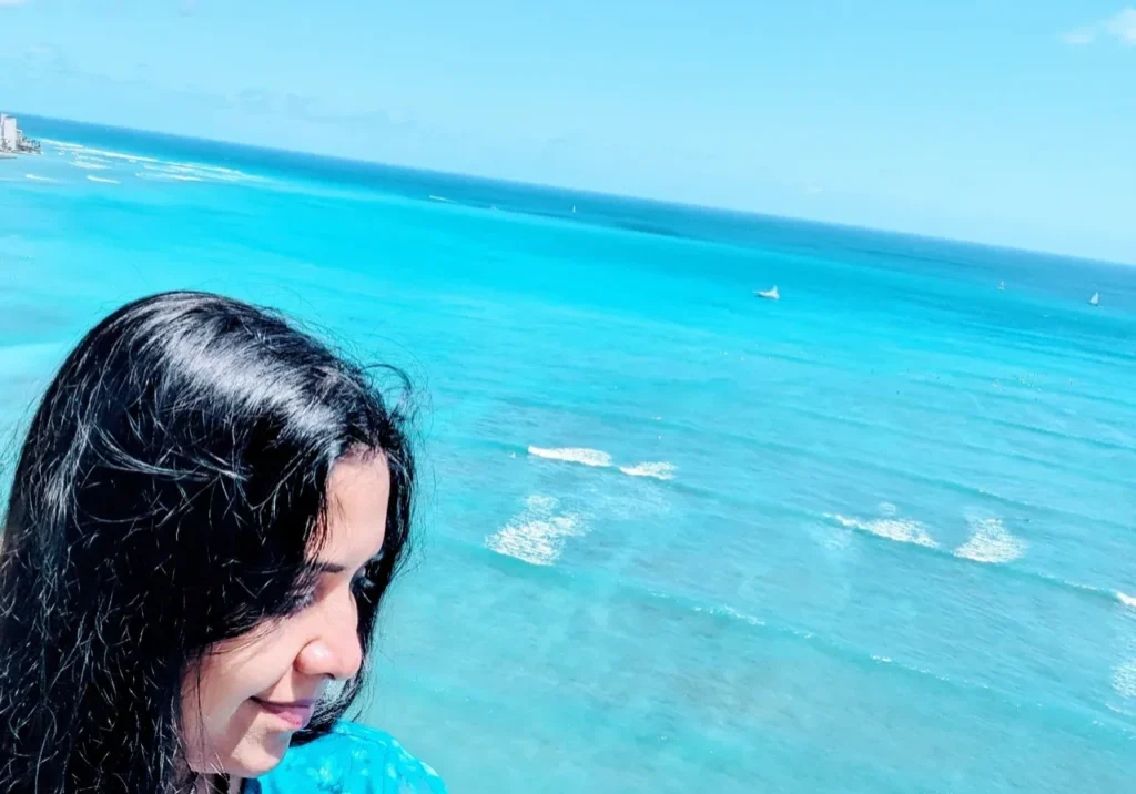 A woman standing on the beach looking at the ocean.