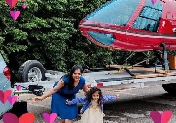 A woman and child standing in front of a red plane.