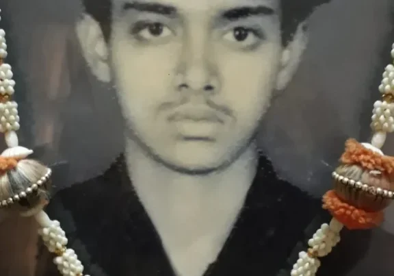 A man wearing a necklace of pearls and orange beads.