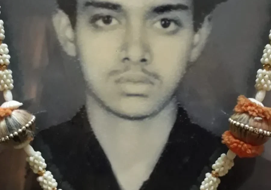 A man wearing a necklace of pearls and orange beads.